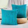 Two bright turquoise plush striped decorative pillowcases standing upright against a light background.