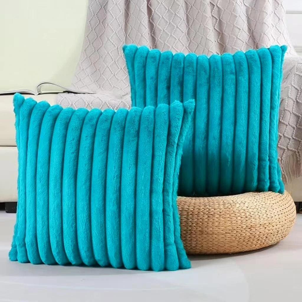 Two bright turquoise plush striped decorative pillowcases standing upright against a light background.
