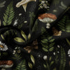 Dark fabric featuring a botanical pattern of forest mushrooms, leaves, and small white flowers.