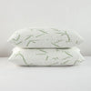 A white bamboo pillow protector with a green leaf pattern lying on a white surface.