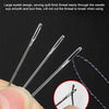 A hand holds several large eyelet needles for sewing, demonstrating easy threading.