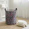 A foldable leopard print laundry basket with a gray and pink pattern sits on a woven rug.