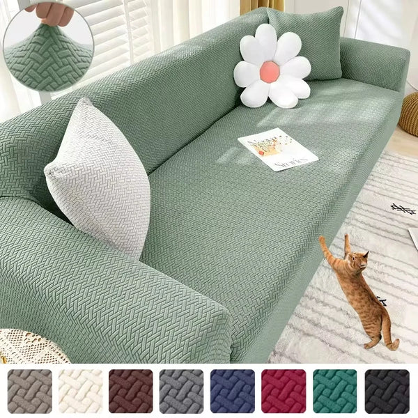 A light green jacquard sofa cover featuring a textured weave and decorative pillows, with a cat resting on the fabric.