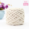 A ball of beige chunky velvet knitting yarn is shown next to purple flowers.