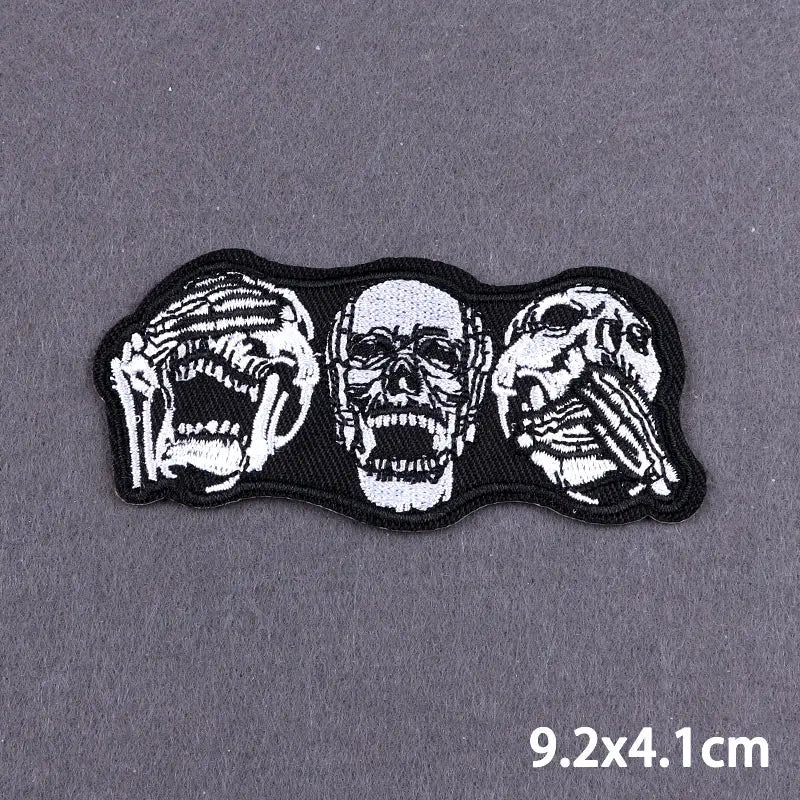 Black embroidered patch featuring three stylized skulls with open mouths