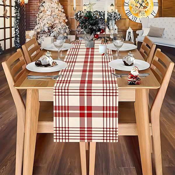 A wooden dining table set for a meal with a red and white plaid linen checkered table runner.
