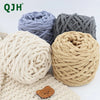 Three balls of chunky velvet knitting yarn in light blue, gray, and beige resting on a cream knitted fabric.