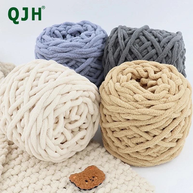Three balls of chunky velvet knitting yarn in light blue, gray, and beige resting on a cream knitted fabric.