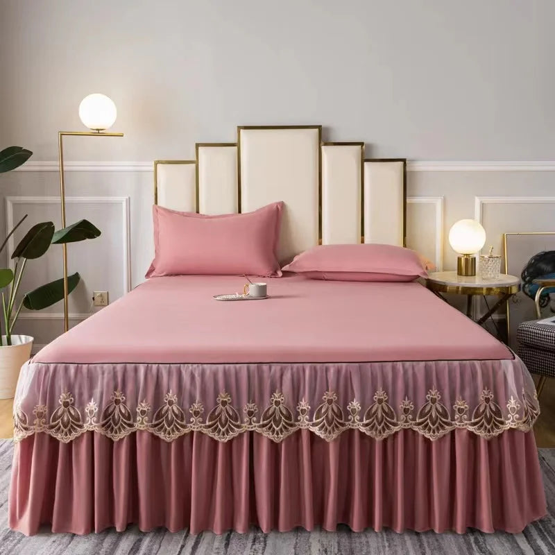 A pink embroidered cotton bedspread set with matching pillows on a bed in a light-colored room.