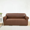 A modern, brown PU leather sofa slipcover placed in a bright living room setting.