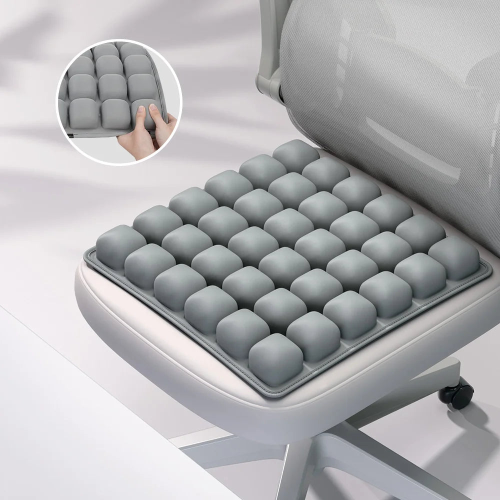 A gray adjustable press-to-inflate seat cushion with individual air cells shown in detail and placed on a chair.