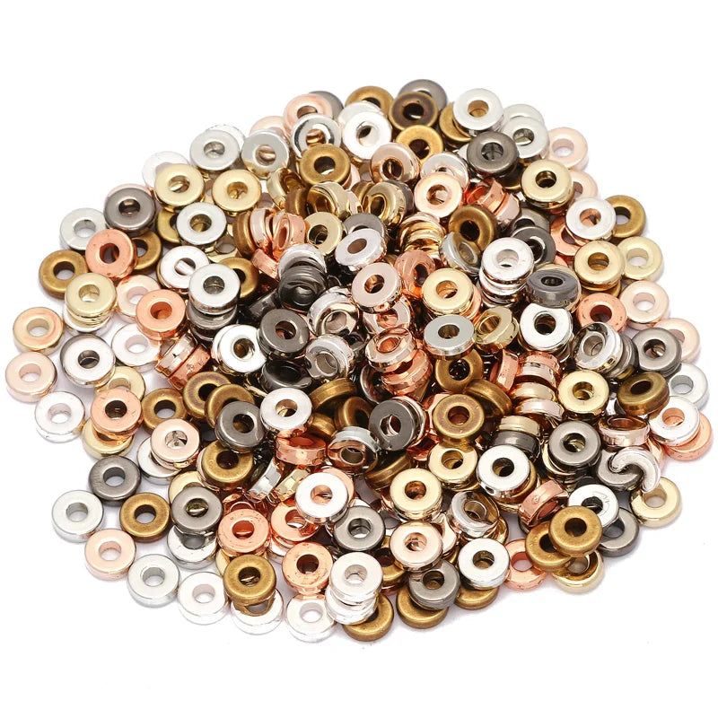 A pile of small, round acrylic flat spacer beads in various colors including gold, silver, bronze, and black.