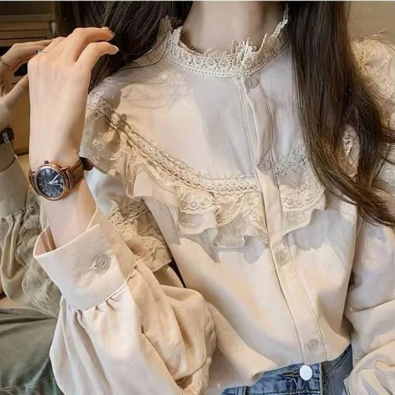 A close-up of a woman wearing a cream lace long sleeve blouse with a high neckline and detailed embroidery.