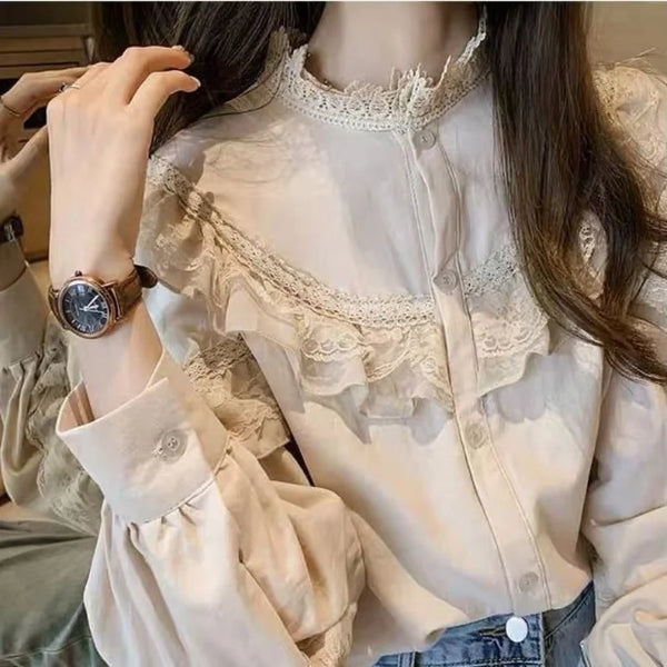 A close-up of a woman wearing a cream lace long sleeve blouse with a high neckline and detailed embroidery.