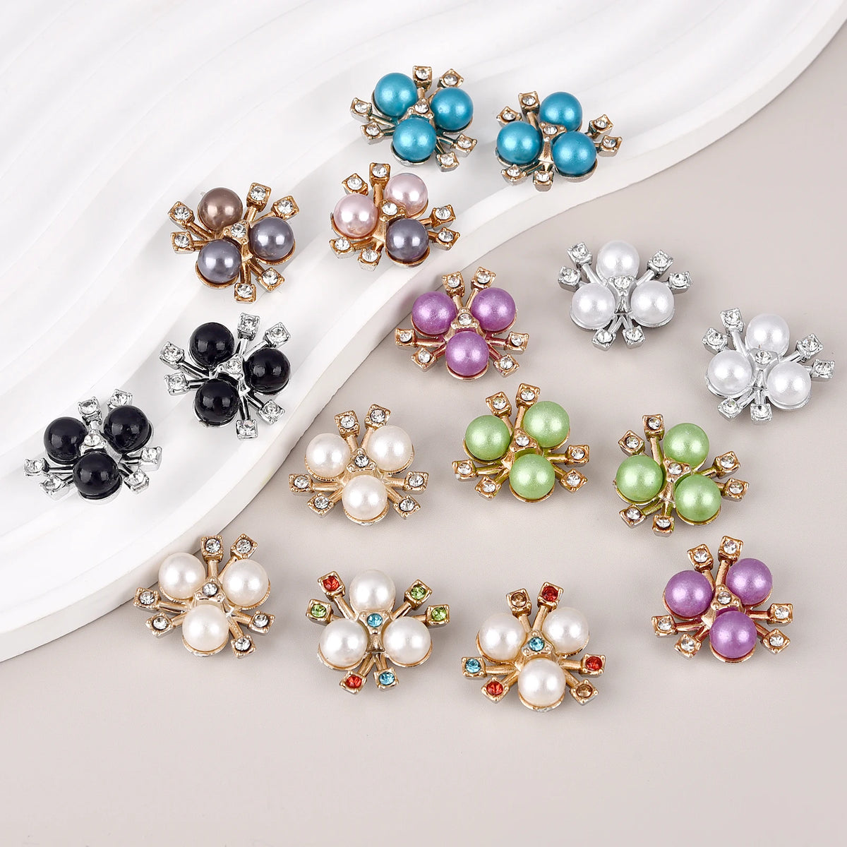A collection of flower-shaped resin button rhinestones in various shades of blue, purple, and silver on a white background.