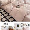 A set of ultra-soft washed cotton quilt bedding in a pale pink color displayed on a bed.