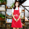 A woman wearing a red waterproof oil-proof PVC kitchen apron stands in front of wooden shelving with plants and books.