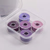 A clear plastic container holding several spools of purple and pink prewound sewing machine bobbin threads.