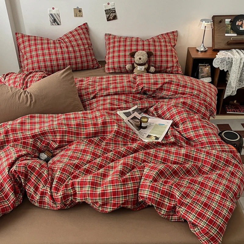 A red and green plaid duvet cover set displayed on a bed with matching pillows and a teddy bear.