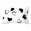 A white decorative pillow cover featuring a pattern of black heart shapes.