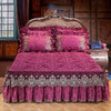 A luxurious magenta quilted bed skirt set with matching pillowcases and a ornate wooden headboard.