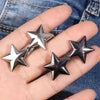 Silver metal star brooch pins are displayed on a hand against a denim background.