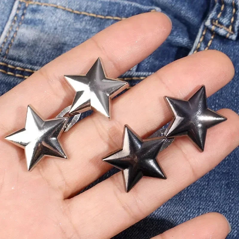 Silver metal star brooch pins are displayed on a hand against a denim background.