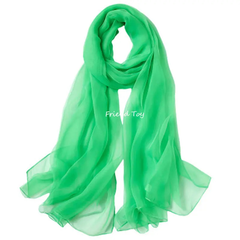 A bright green sheer scarf draped and folded, suitable for sensory play.