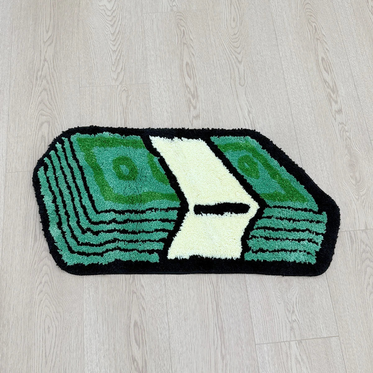 A rectangular rug featuring a green and white design resembling folded dollar bills on a light wood floor.