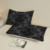 A set of three black and gray floral skull patterned bed sheets displayed on a white surface.