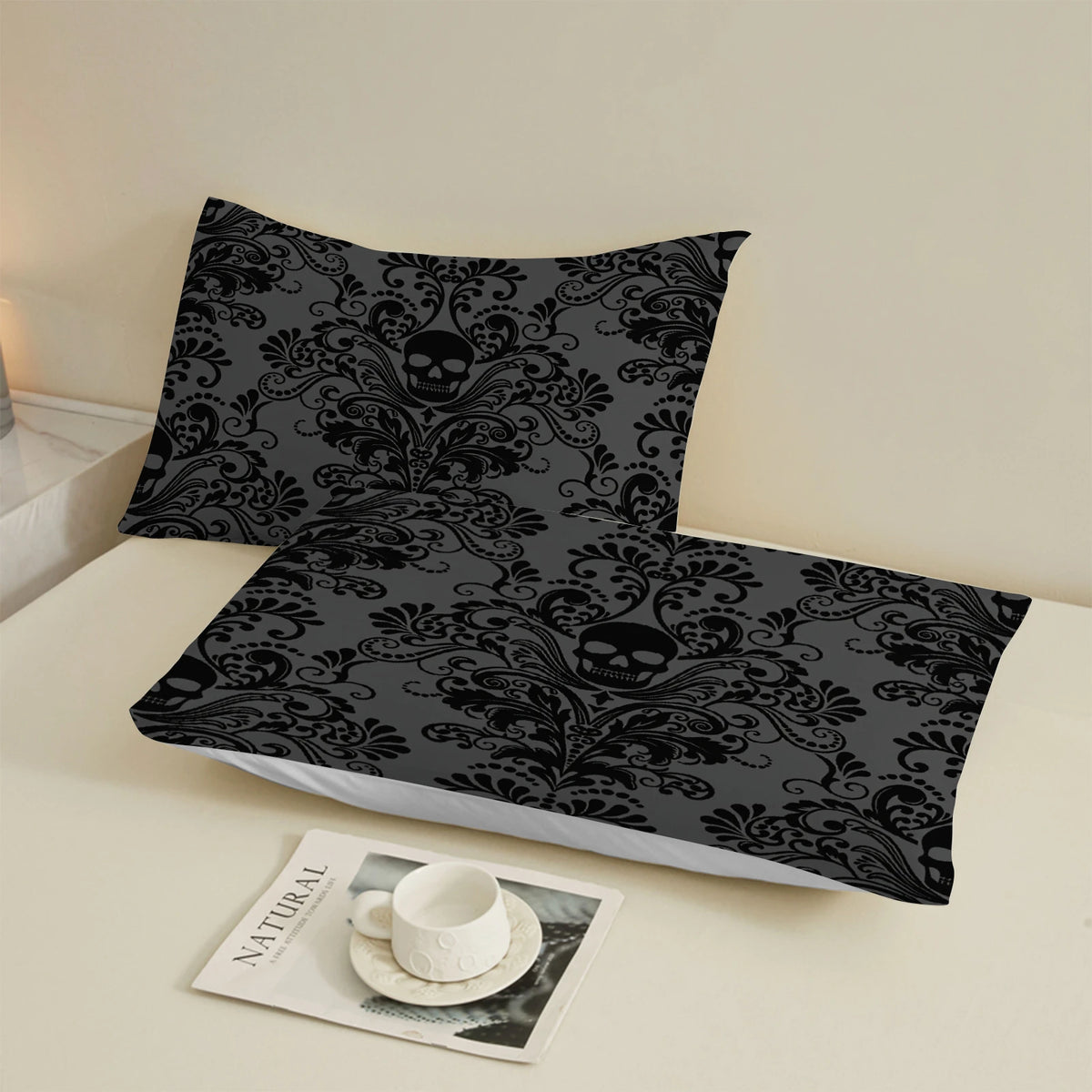 A set of three black and gray floral skull patterned bed sheets displayed on a white surface.