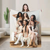 A group of five women posing with a white fleece throw blanket in a studio setting.
