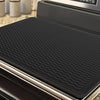 A black heat-resistant silicone stove top cover mat is shown inside a stainless steel appliance.
