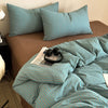A striped teal duvet cover set is displayed on a bed with brown bedding and a dark nightstand.