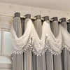 Gray sheer curtains with white lace trim hanging on a rod against a light-colored wall.
