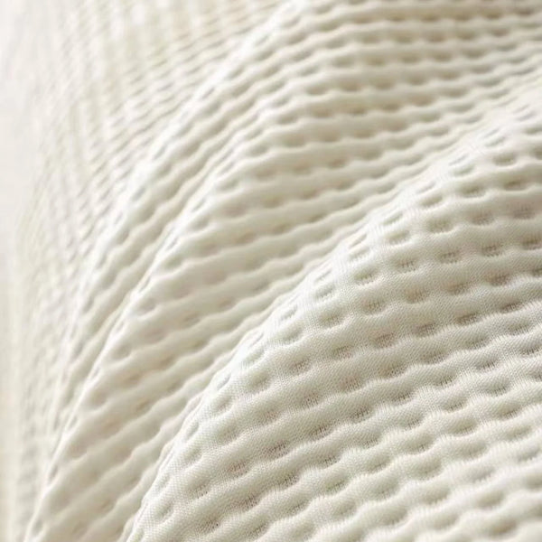 Close-up of a white anti-slip summer sofa cover with a textured, quilted pattern.