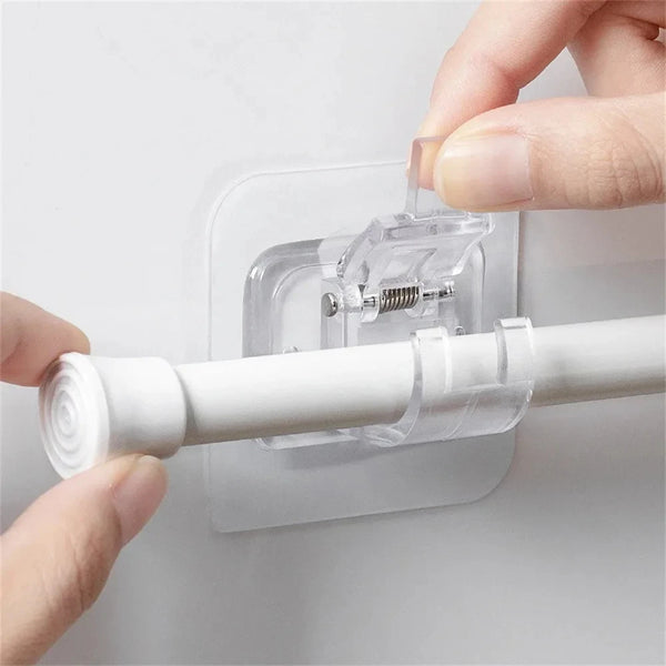 A hand is installing a clear self-adhesive curtain rod clip onto a white window frame.