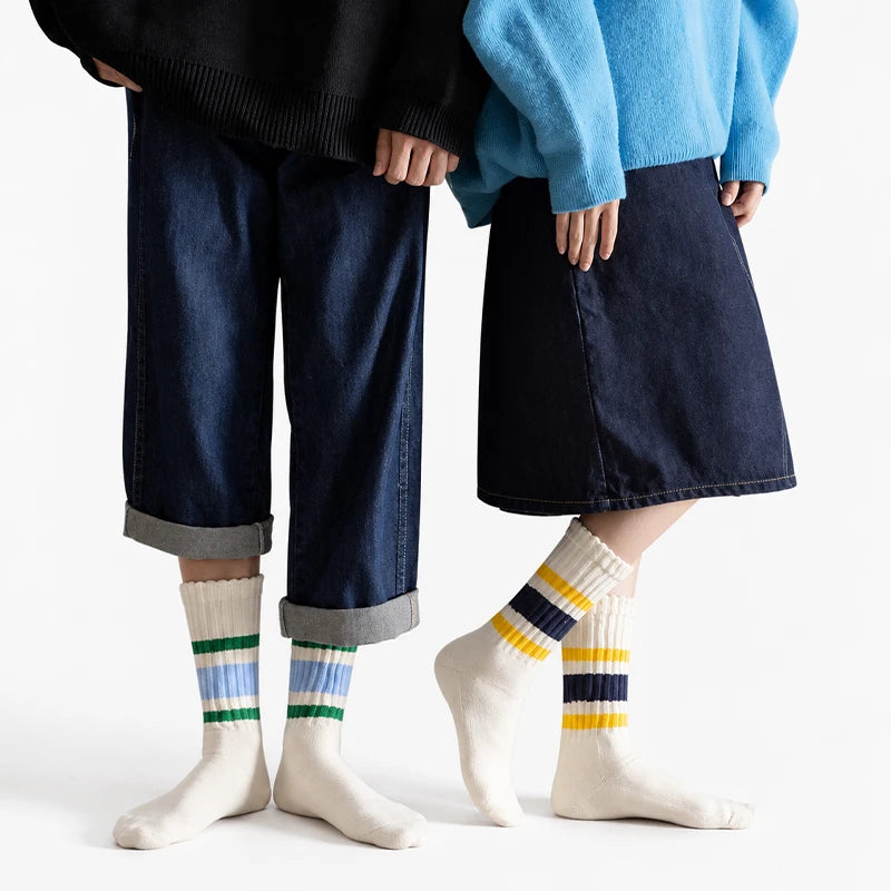 A person wearing dark denim pants and a black sweater is holding the hands of another person wearing a light blue top and a d