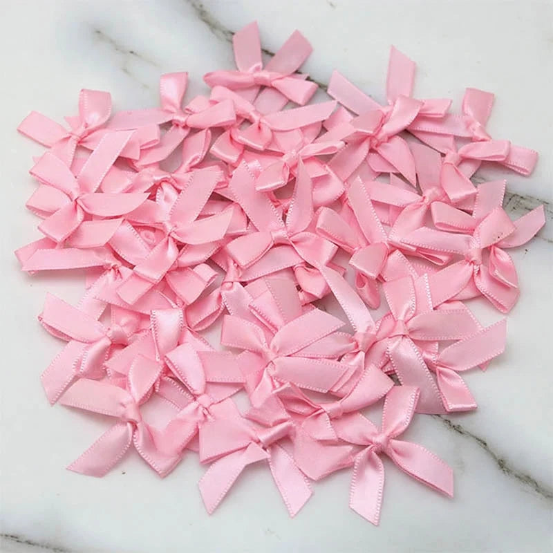 A pile of small pink satin ribbon bows for crafts and decor