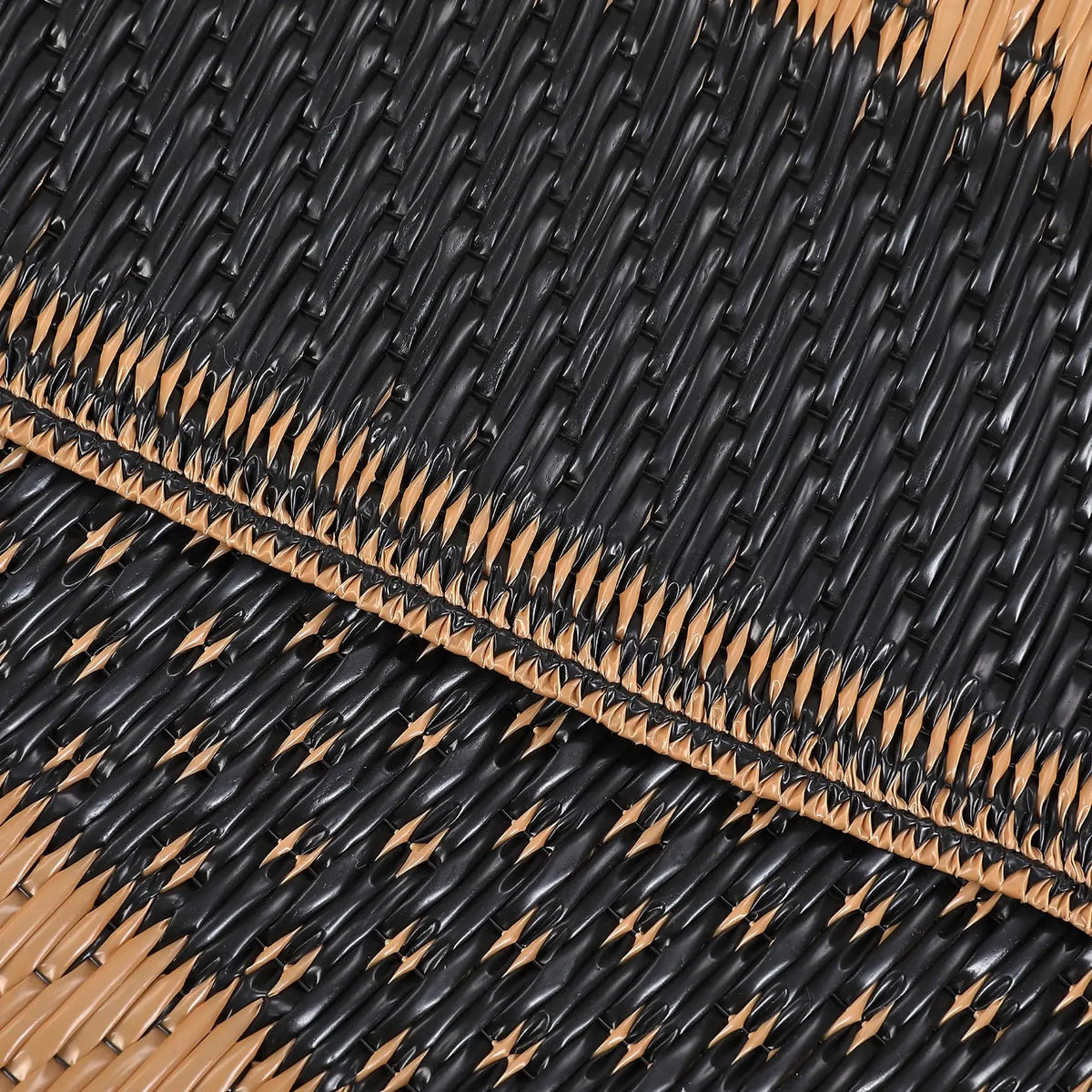 Close-up of a black and tan plastic straw mat with woven texture and visible stitching.