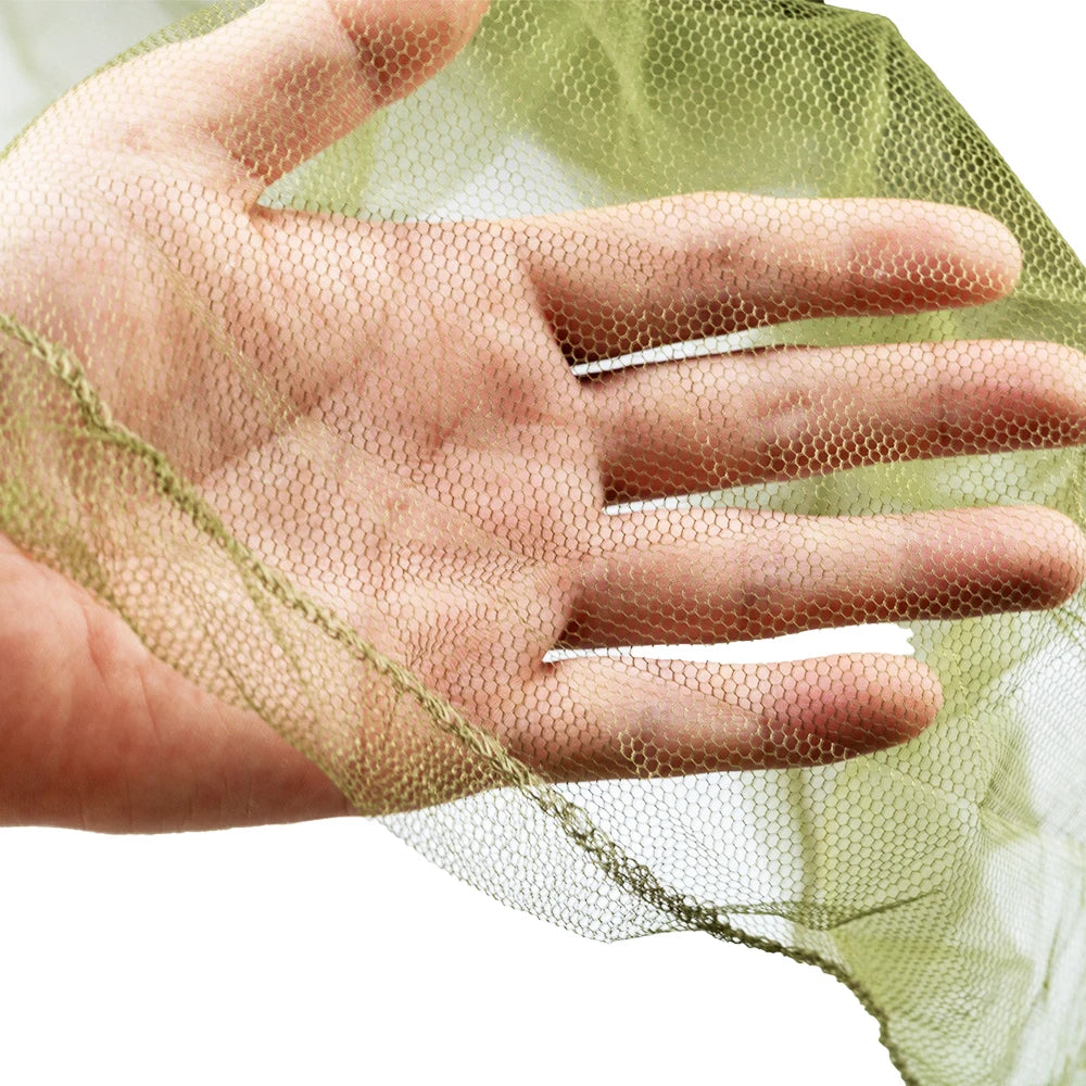 A hand is holding a sheer green mosquito net fabric over the palm.