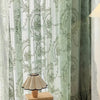 Sheer floral lace curtain panels in green and white patterns hanging indoors