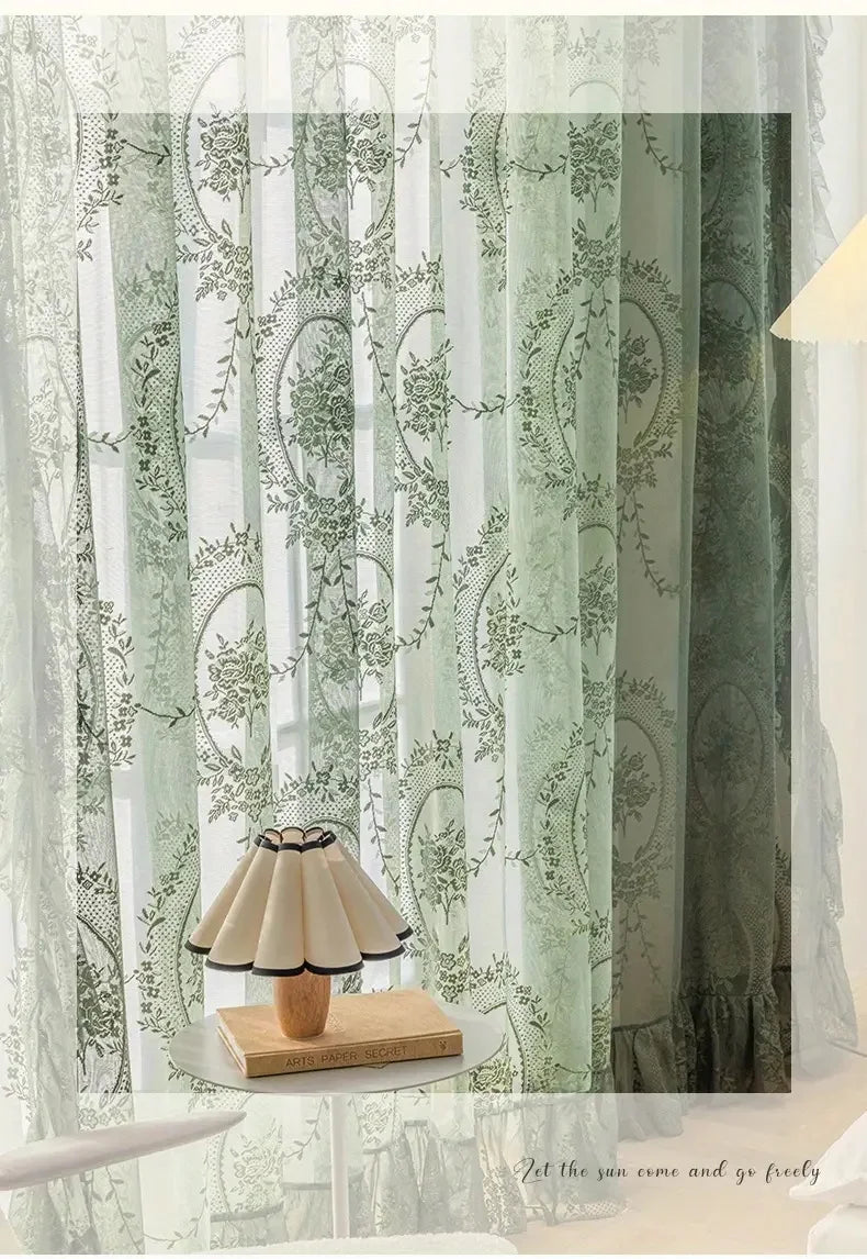 Sheer floral lace curtain panels in green and white patterns hanging indoors
