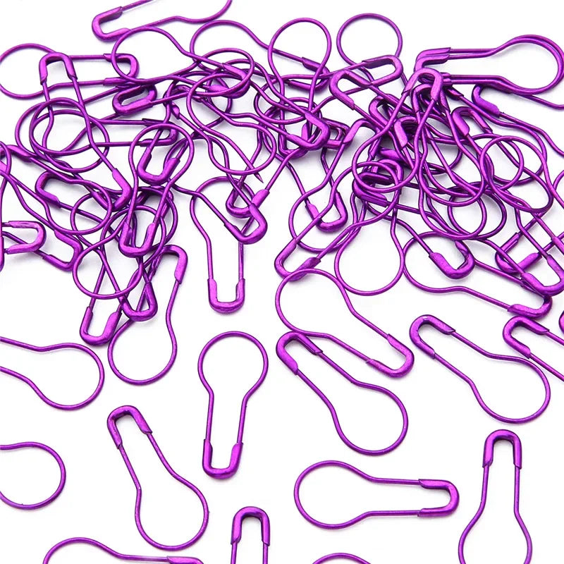 A pile of purple safety bulb pins for knitting and sewing.