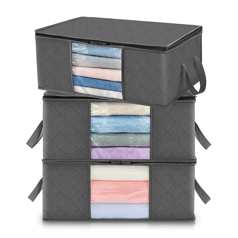 A stack of three dark gray foldable storage boxes, each containing neatly folded fabric items in various pastel colors.