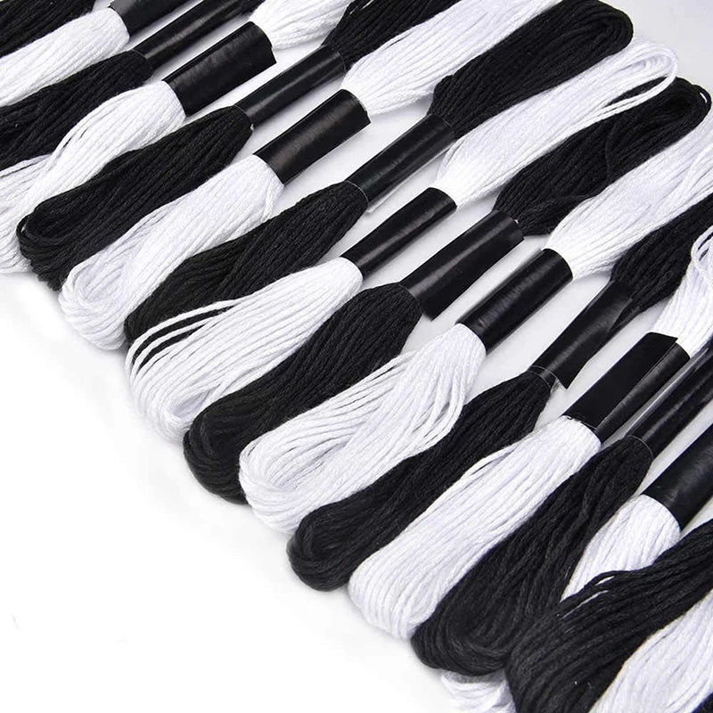 A collection of black and white embroidery floss threads laid out in a line.