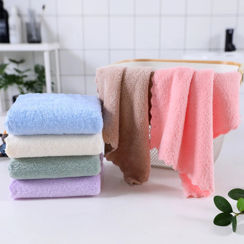 A set of ten luxury coral velvet cleaning face towels in various pastel shades stacked next to a wooden tray.