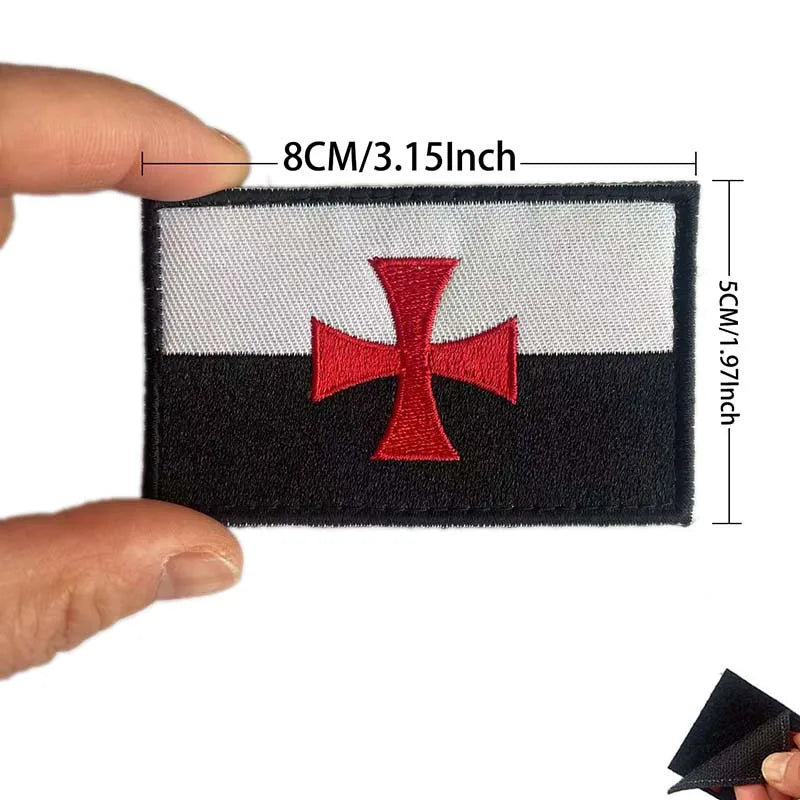 Black and white embroidered patch featuring a red cross on a flag design
