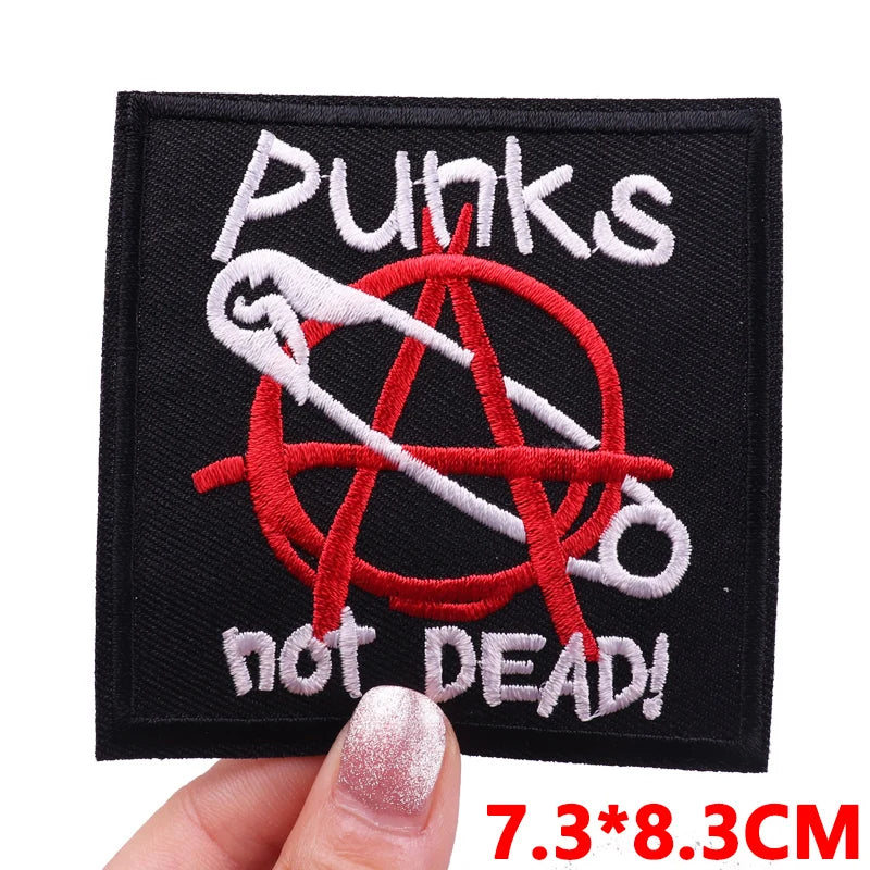 Black embroidery patch featuring a punk aesthetic with a skull and crossbones design in red and white thread.