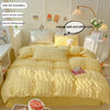 A yellow soft textured duvet cover set with pillowcases displayed on a bed, next to a lamp and flowers.